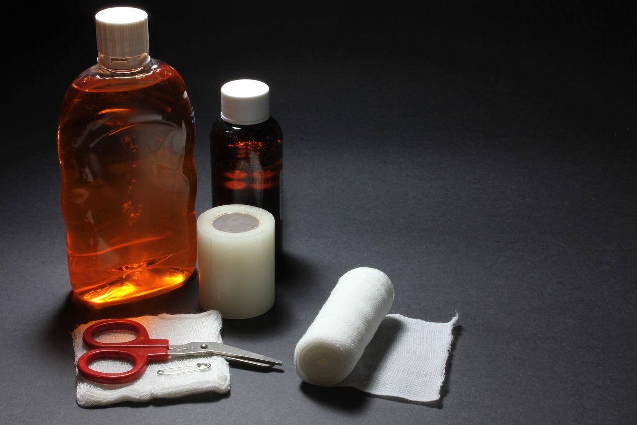 First aid supplies including bandages, bottles, and scissors laid out on a dark surface.